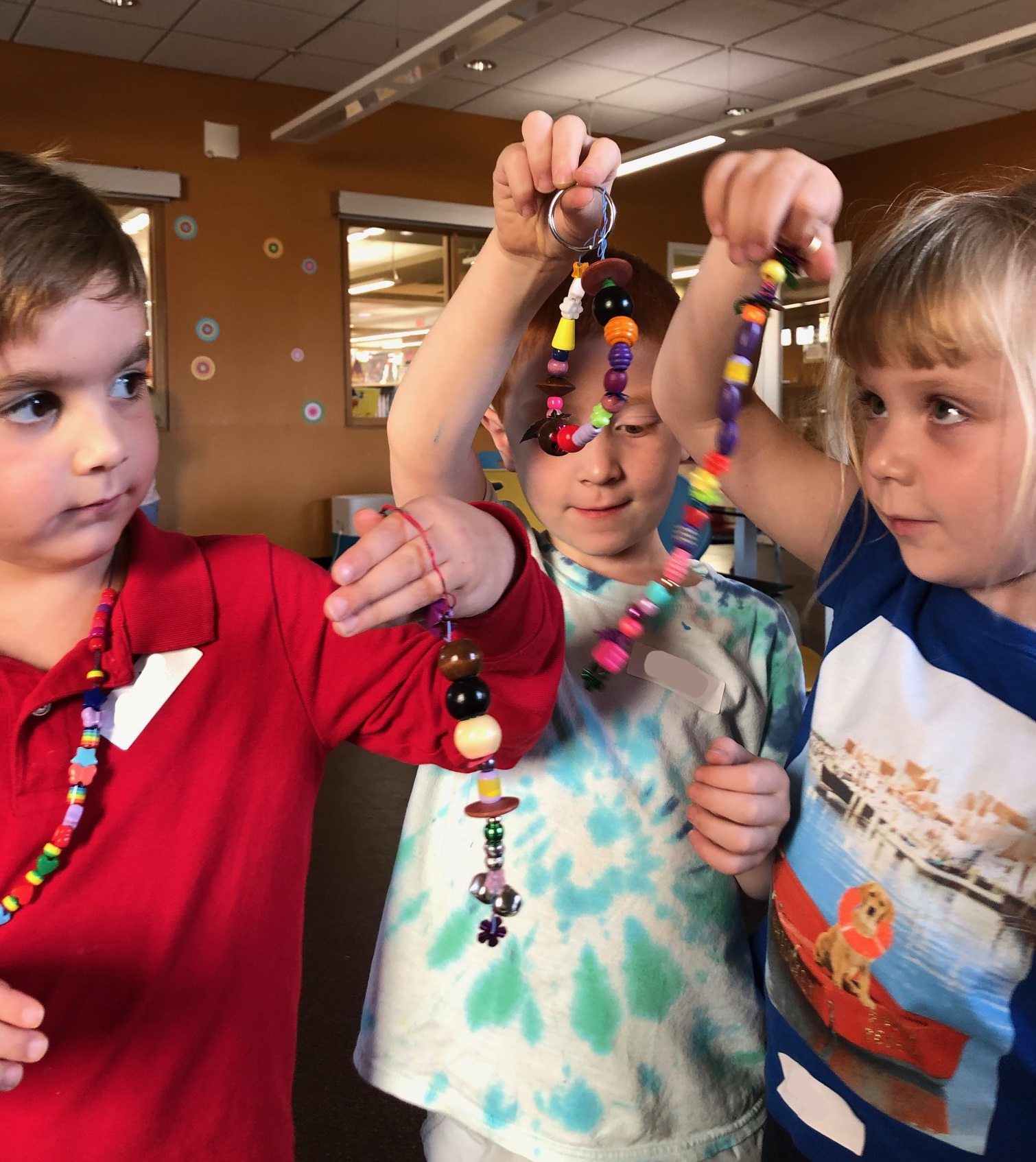 three white children holding up strings of beads