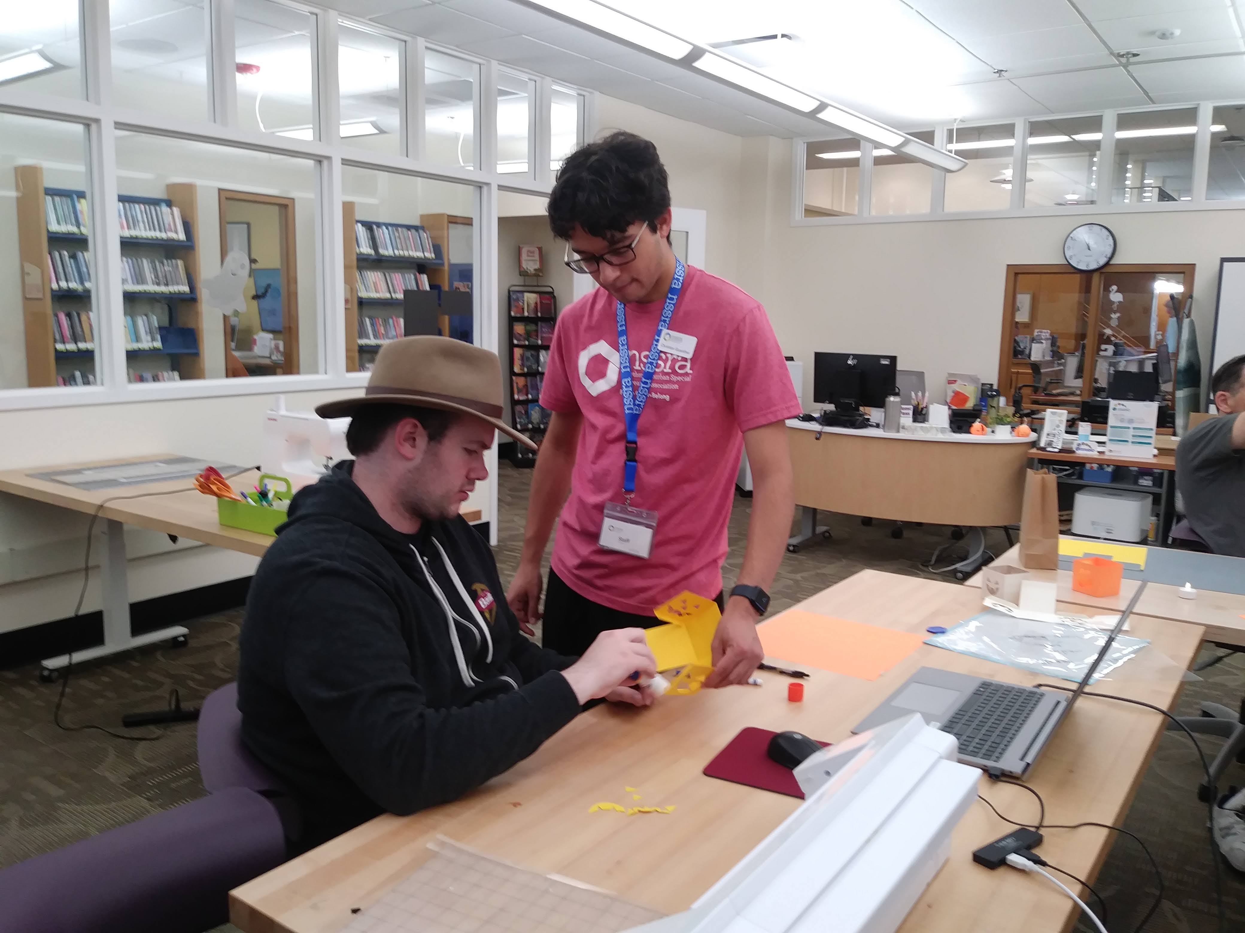 Two adults in The Studio working on a paper design after it was cut with the Silhouette Cameo.