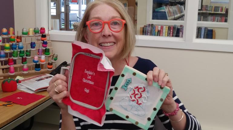 A smiling patron showing off their embroidery projects.